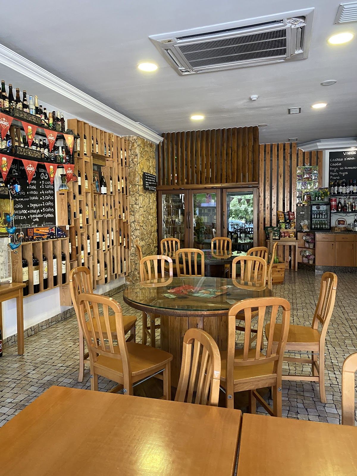 Interior da Taverna Pica Cebola em Fátima, com mesas de madeira e garrafeira ao fundo